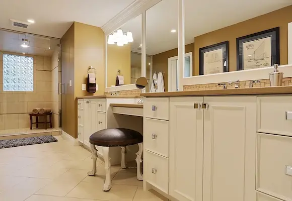 custom white bathroom vanity cabinets with a leather stool