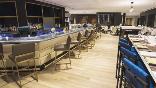 the bar area of a restaurant with blue chairs