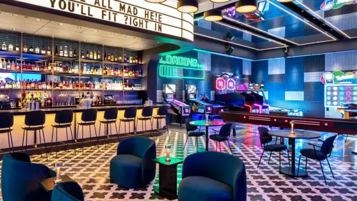 a bar with colorful chairs and a neon sign