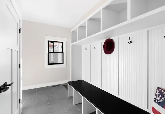 mudroom with custom white woodworking and a black bench