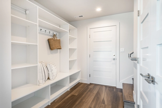 newly renovated mud room with white finishes and custom wood flooring